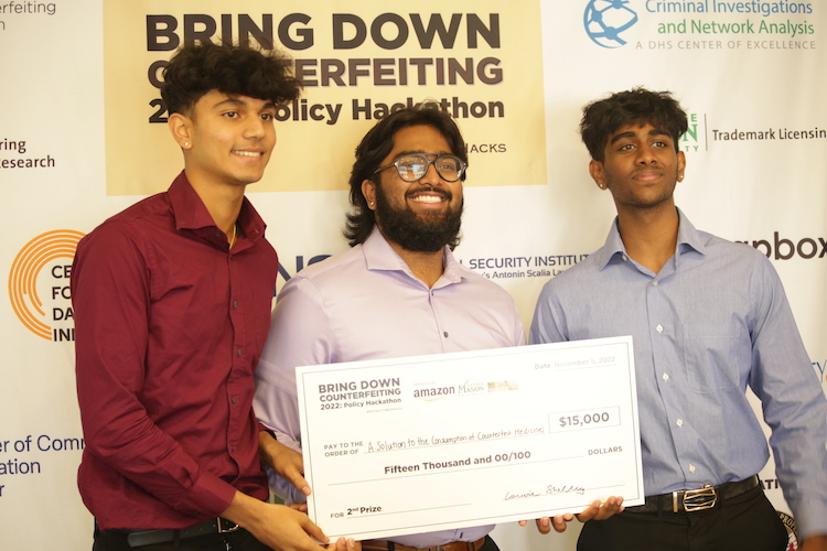 three men hold up a cardboard check